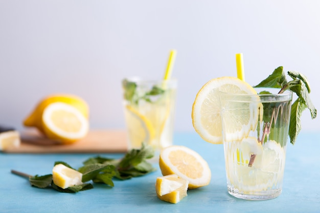 Homemade fresh detox water with lemons over gray background and sitting on blue vintage desk