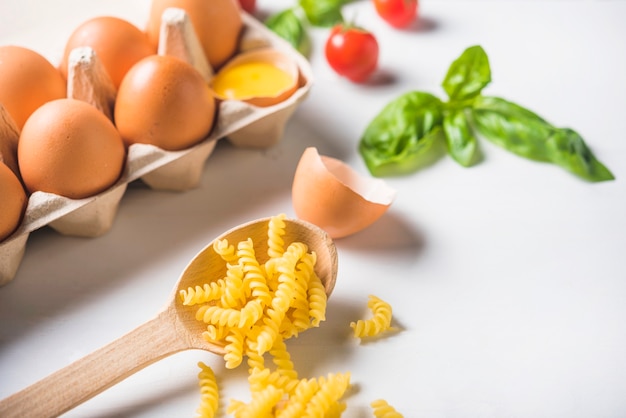 Homemade fusilli pasta with ingredients on white background