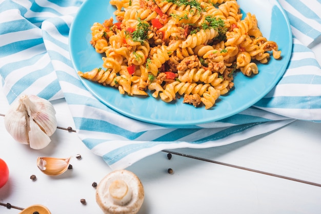 Homemade fusilli pasta with ingredients on wooden table