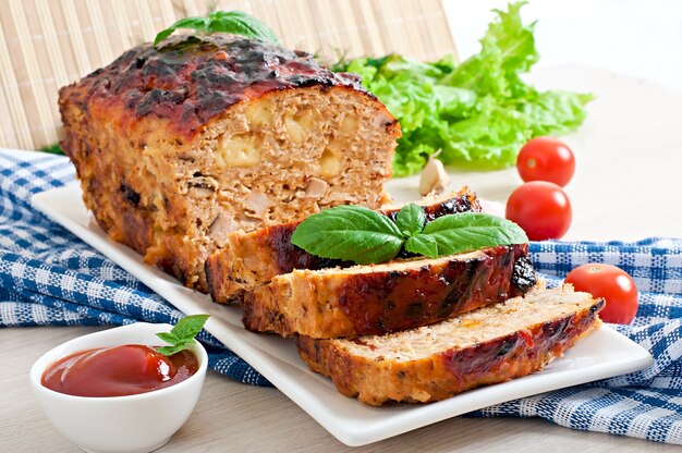 Homemade ground meatloaf with ketchup and basil