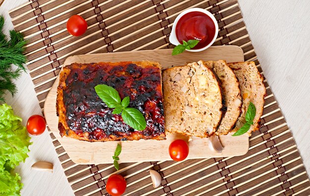 Homemade ground meatloaf with ketchup and basil