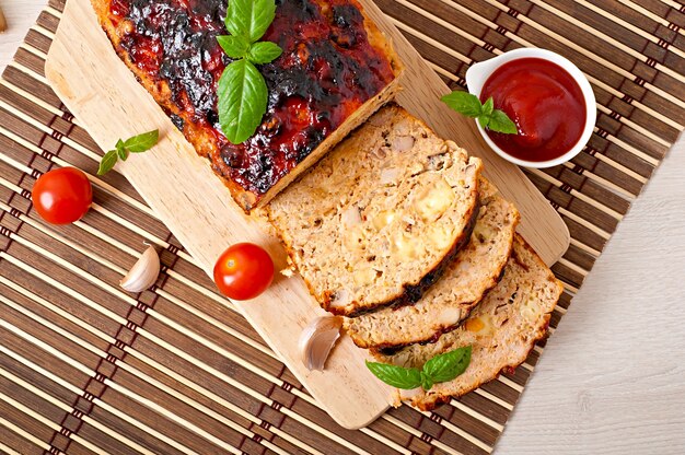 Homemade ground meatloaf with ketchup and basil