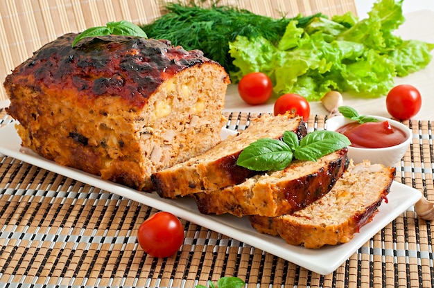 Homemade ground meatloaf with ketchup and basil