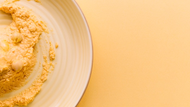 Free photo homemade hummus on plate against beige background