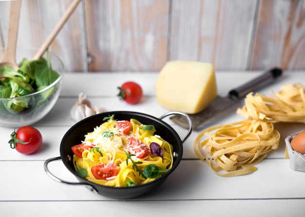 Homemade italian spaghetti pasta garnish with cheeses; basil leaves and slice of tomato