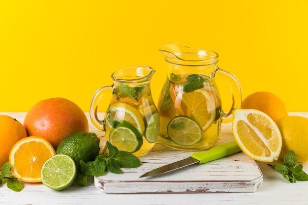 Free photo homemade lemonade jugs with yellow background