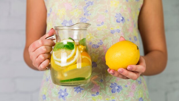 Homemade lemonade and lemon held by a woman