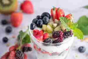 Free photo homemade muesli, bowl of oat granola with yogurt, fresh blueberries, mulberry, strawberries, kiwi, mint and nuts board for healthy breakfast, copy space. healthy breakfast concept. clean eating.