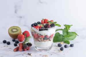 Free photo homemade muesli, bowl of oat granola with yogurt, fresh blueberries, mulberry, strawberries, kiwi, mint and nuts board for healthy breakfast, copy space. healthy breakfast concept. clean eating.