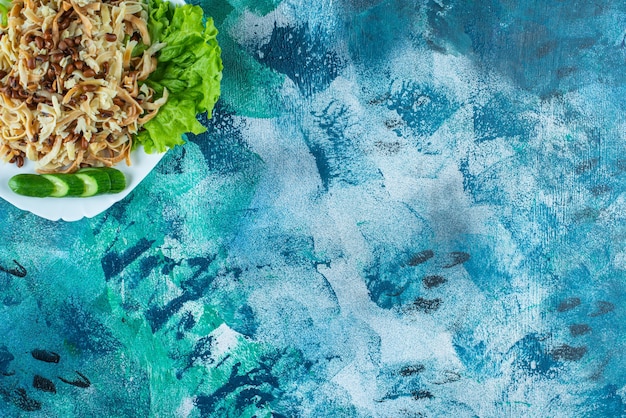 Tagliatella fatta in casa con fetta di cetriolo su un piatto, sul tavolo blu.