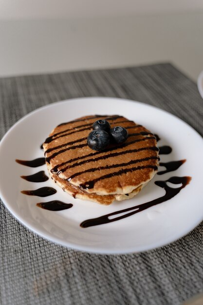 Homemade pancakes with blueberries on top and with chocolate syrup poured on it