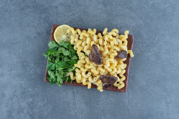 Homemade pasta with dried meat on brown plate. 