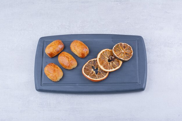 Домашняя выпечка с сушеным апельсином на темной тарелке.