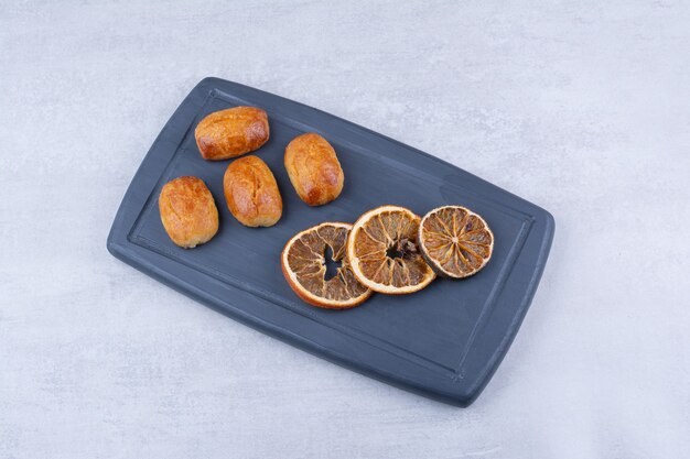 Homemade pastries with dried orange on dark plate.