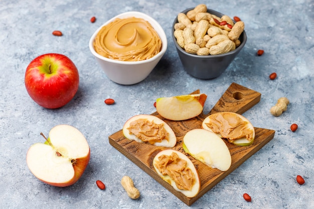 Homemade peanut butter with peanuts on grey concrete table, top view