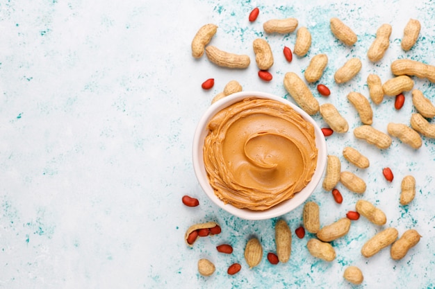 Free photo homemade peanut butter with peanuts on grey concrete table, top view