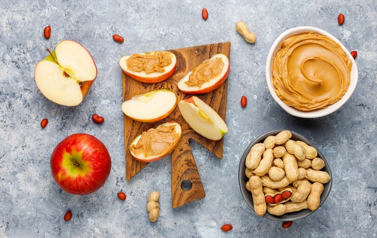 Homemade peanut butter with peanuts on grey concrete table, top view
