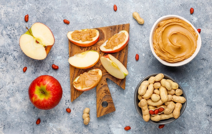 Homemade peanut butter with peanuts on grey concrete table, top view