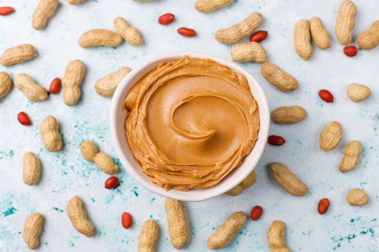 मुफ़्त फोटो homemade peanut butter with peanuts on grey concrete table, top view