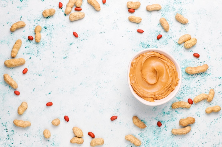 मुफ़्त फोटो homemade peanut butter with peanuts on grey concrete table, top view