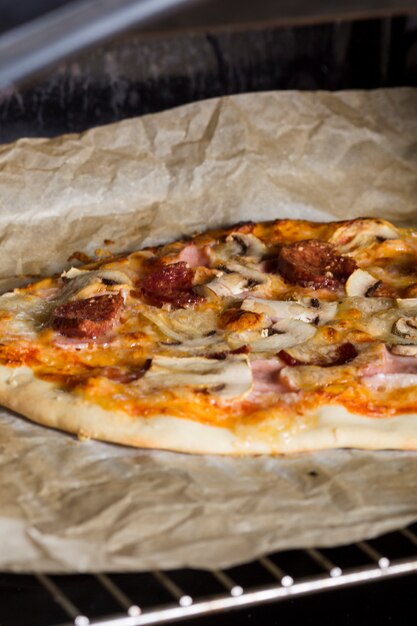 Homemade pizza on parchment paper over the grate