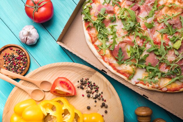 ピーマンと自家製ピザ。トマトのニンニクと木製のテーブルの上のスパイス