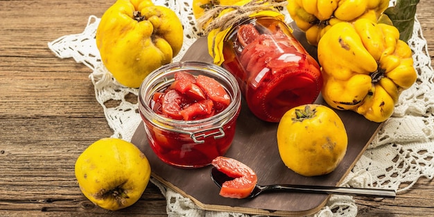 Homemade quince jam in a glass jar. fresh fruits, sweet marmalade,vintage arrangement. old wooden background, banner format