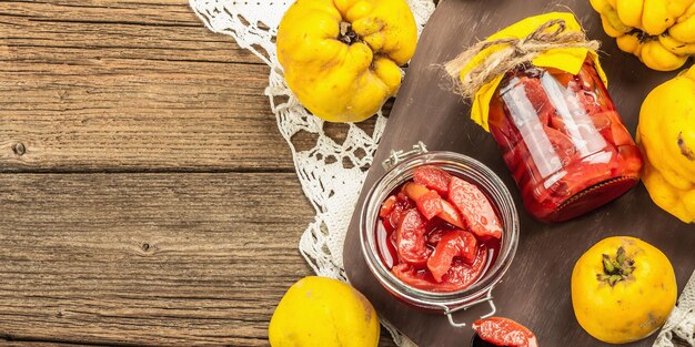 Homemade quince jam in a glass jar. fresh fruits, sweet marmalade,vintage arrangement. old wooden background, banner format