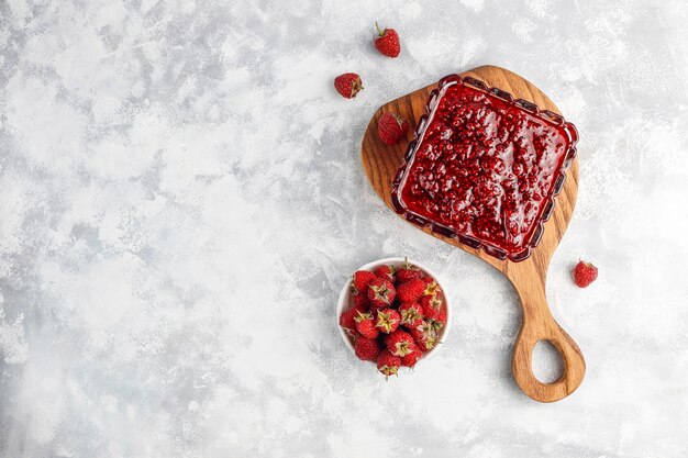 Homemade raspberry jam with fresh raspberries on concrete , top view