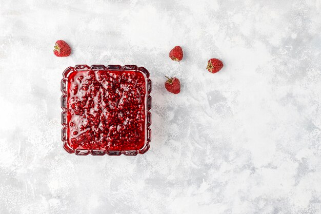 Homemade raspberry jam with fresh raspberries on concrete , top view