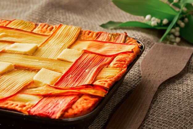 Free photo homemade rhubarb pie on a table with rough linen bedding closeup horizontal layout selective focus on a freshly baked tart