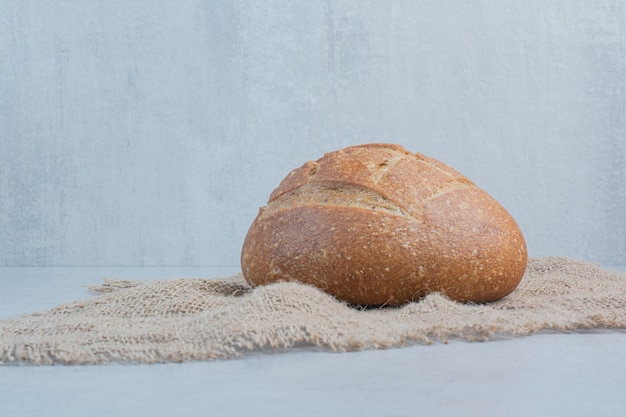 Homemade rye bread on burlap on marble background. High quality photo