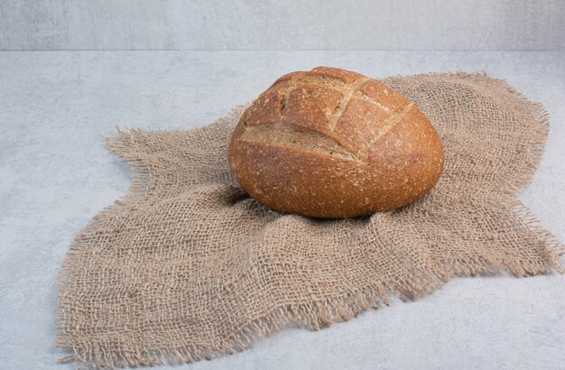 Homemade rye bread on burlap on marble background. High quality photo