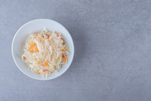 Homemade sauerkraut in bowl , on the marble background.