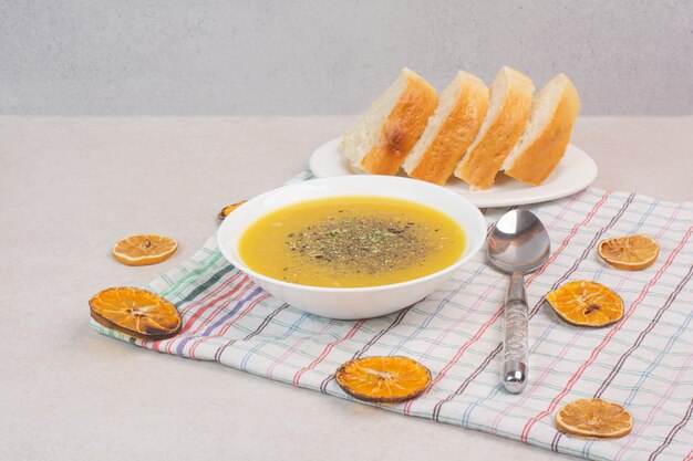 Homemade soup and slices of bread on tablecloth.