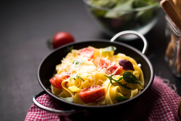 Homemade spaghetti pasta with grated cheese and cherry tomatoes in container