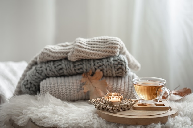 Foto gratuita natura morta fatta in casa con maglioni lavorati a maglia e una tazza di tè su uno sfondo sfocato.