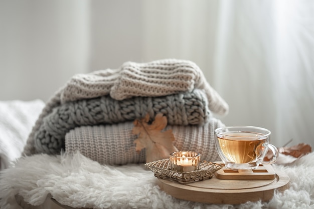 Homemade still life with knitted sweaters and a cup of tea on a blurred background.