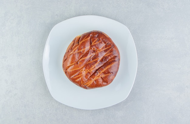 Homemade sweet bun on white plate. 