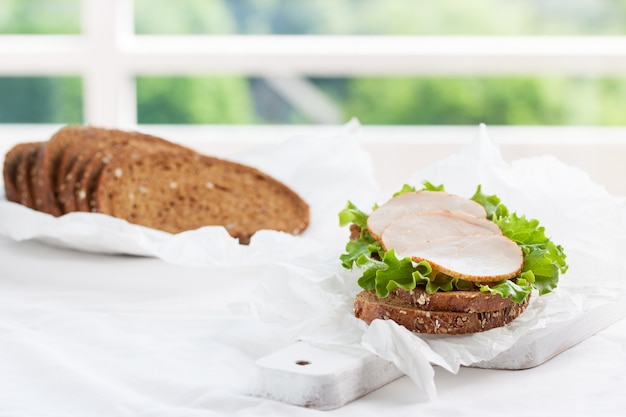 Free photo homemade tasty sandwich with salad leaves and ham on a cutting board