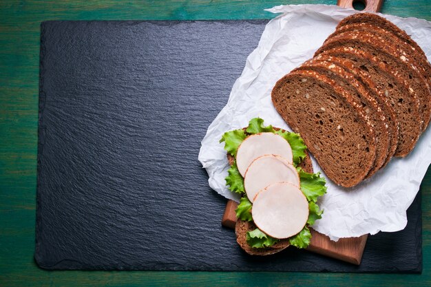 Homemade tasty sandwich with salad leaves and ham on a cutting board