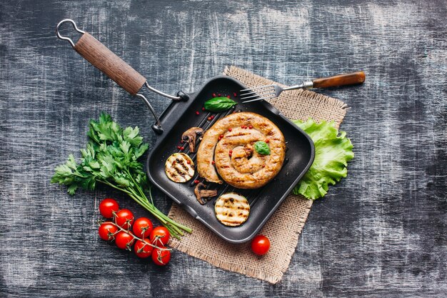 Homemade tasty spiral grilled sausage with healthy vegetable in pan