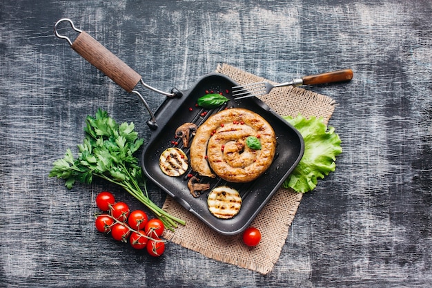 Домашняя вкусная спиральная колбаса на гриле с полезными овощами в сковороде