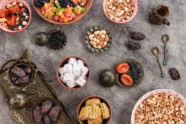 Домашние турецкие сладости с сухофруктами и орехами с ложками на бетонном фоне