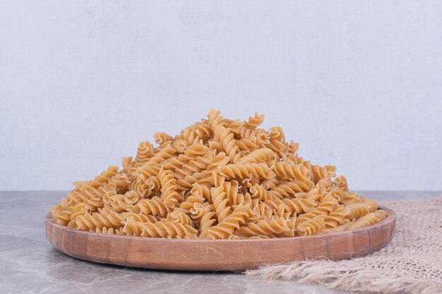 Homemade uncooked pastas in a wooden platter on rustic surface