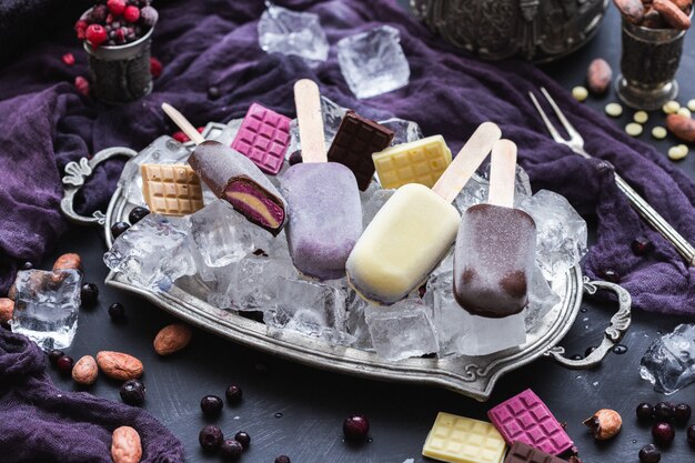 Homemade vegan ice cream and chocolate bars on ice cubes in a metal plate
