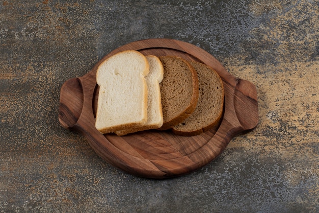 Homemade white and black bread slices on wooden board