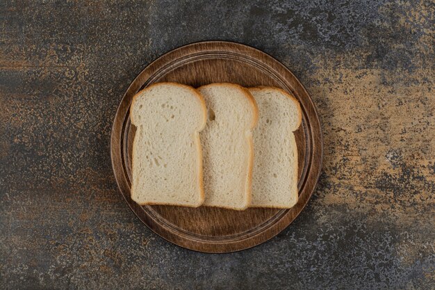 Homemade white bread slices on wooden board