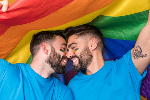 Homosexual couple gently cuddling on rainbow flag