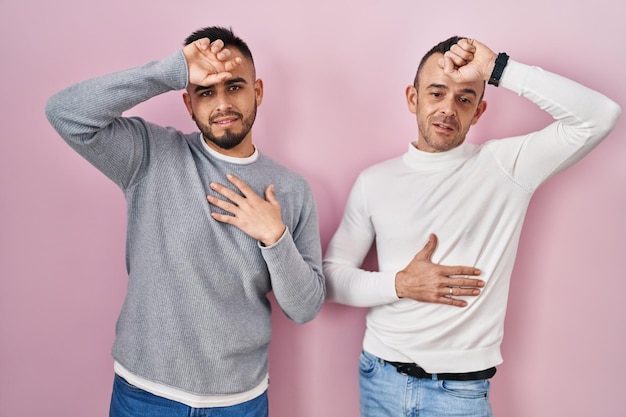 無料写真 ピンクの背景の上に立って、病気や発熱、インフルエンザや風邪、ウイルスの病気のために額に触れる同性愛者のカップル